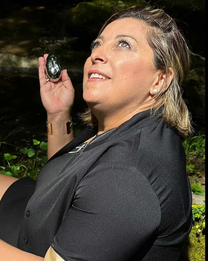 Melyssa Jennadi, massothérapeute, tenant un galet magnétique de massage en forêt